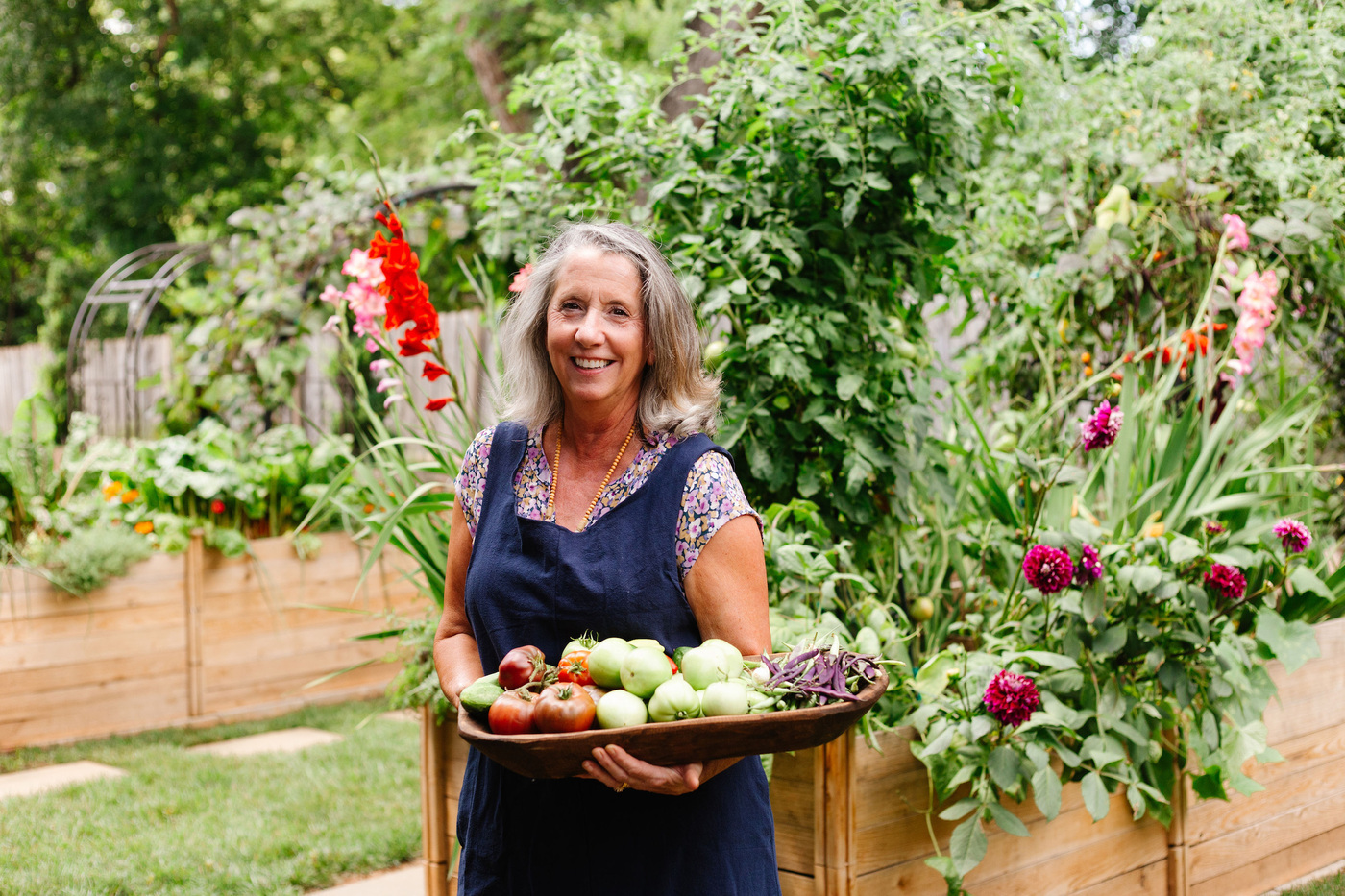 Sara Rubens, a kitchen garden consultant at Seed to Sanctuary, standing in a lush home garden, offering expert guidance on growing plants.