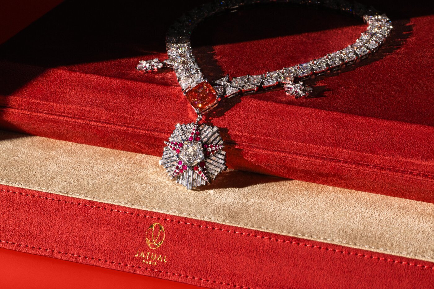 Close-up of Jatual Paris’s Pobeda necklace resting on a red velvet case, showcasing a 23.4-carat vivid red diamond and intricate diamond-ruby design.