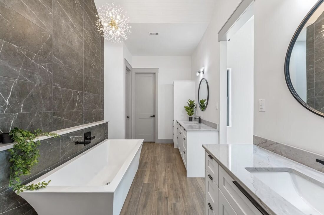 Custom primary bathroom with freestanding tub and marble feature wall by Fin Home Custom Contracting, Possum Kingdom Lake, TX
