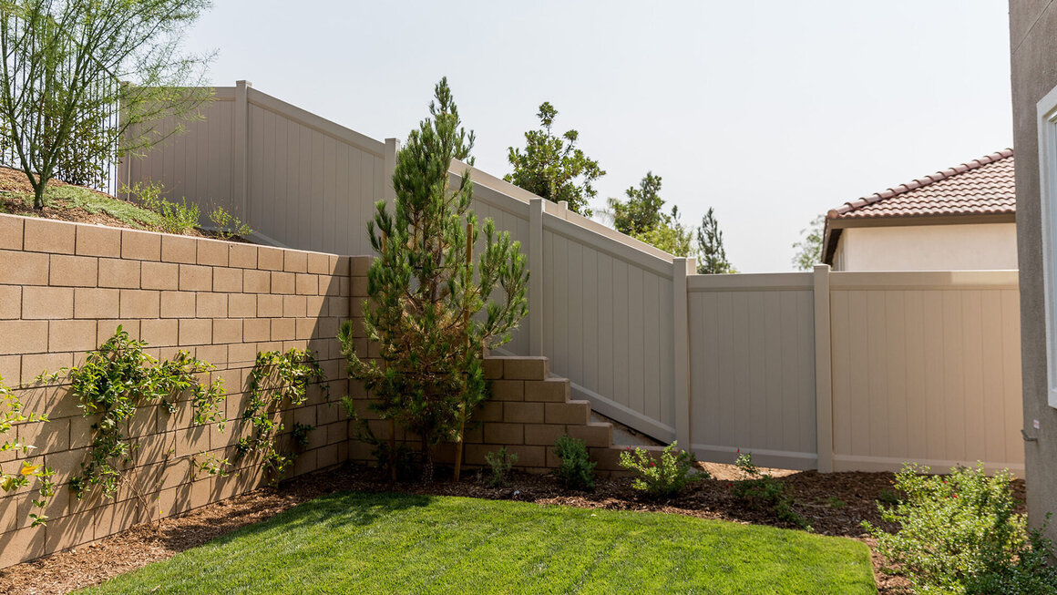 Vinyl privacy fence installed around a landscaped residential backyard